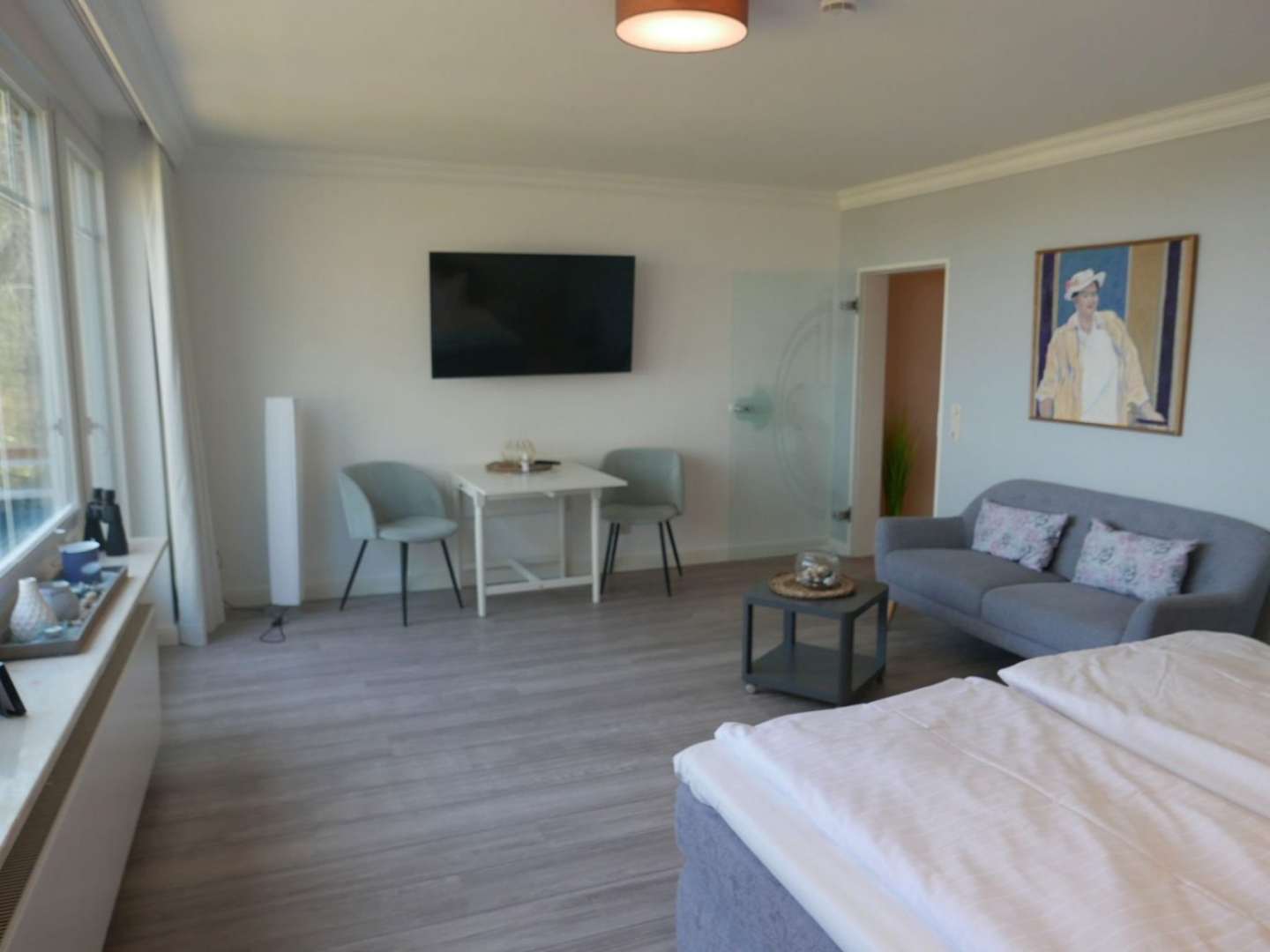 Wohn und Schlafzimmer mit einem Doppelbett, einem Tisch mit 2 Stühlen und einem Sofa