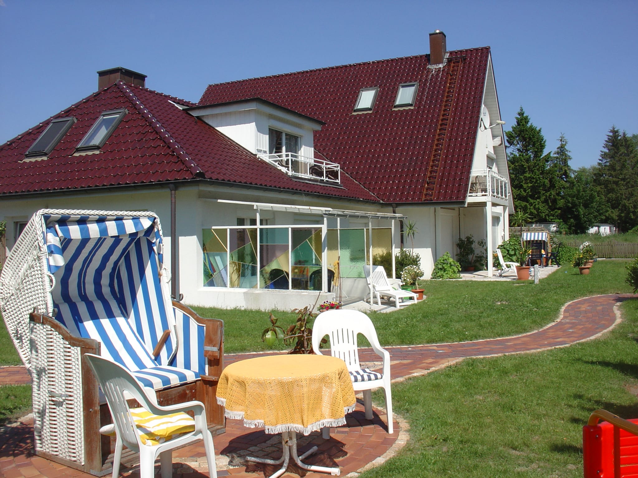 Strandkorb, Tisch und Stühle im Garten, Haus im Hintergrund