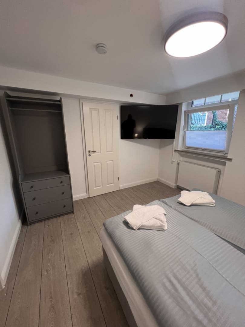 Doppelbett mit Fernseher an der Wand und einem Kleiderschrank in der Ecke