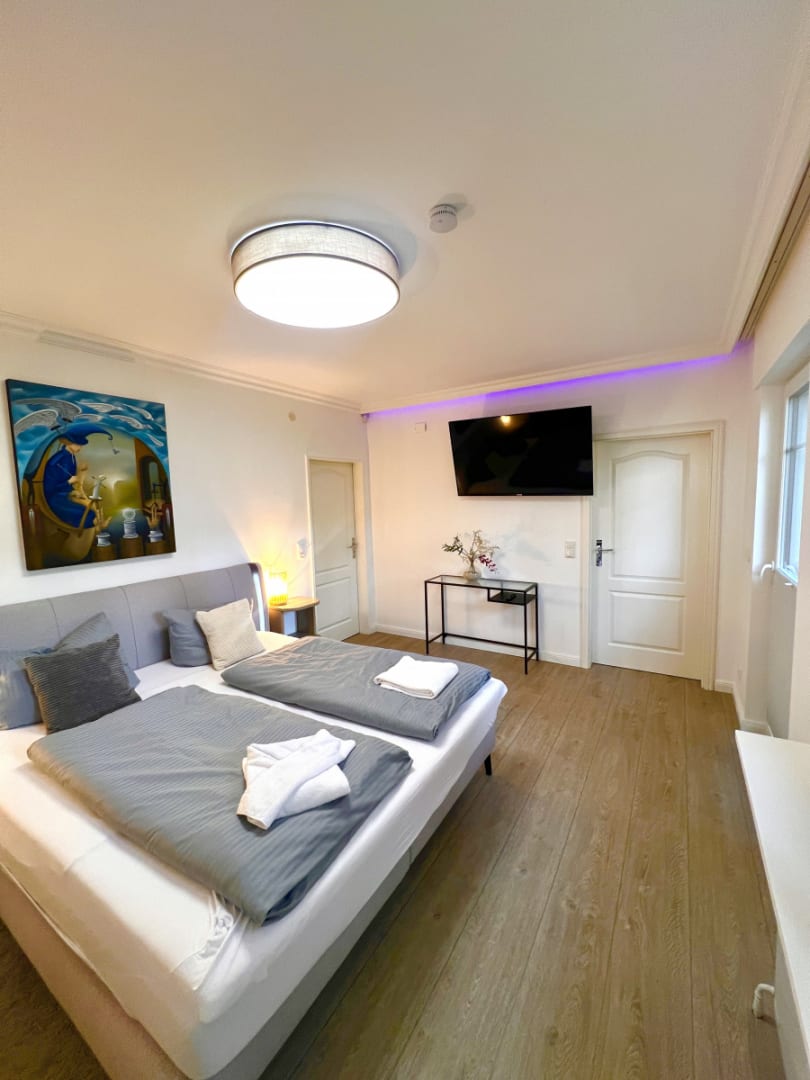 Schlafzimmer mit Doppelbett. Fernseher und Bild an der Wand.