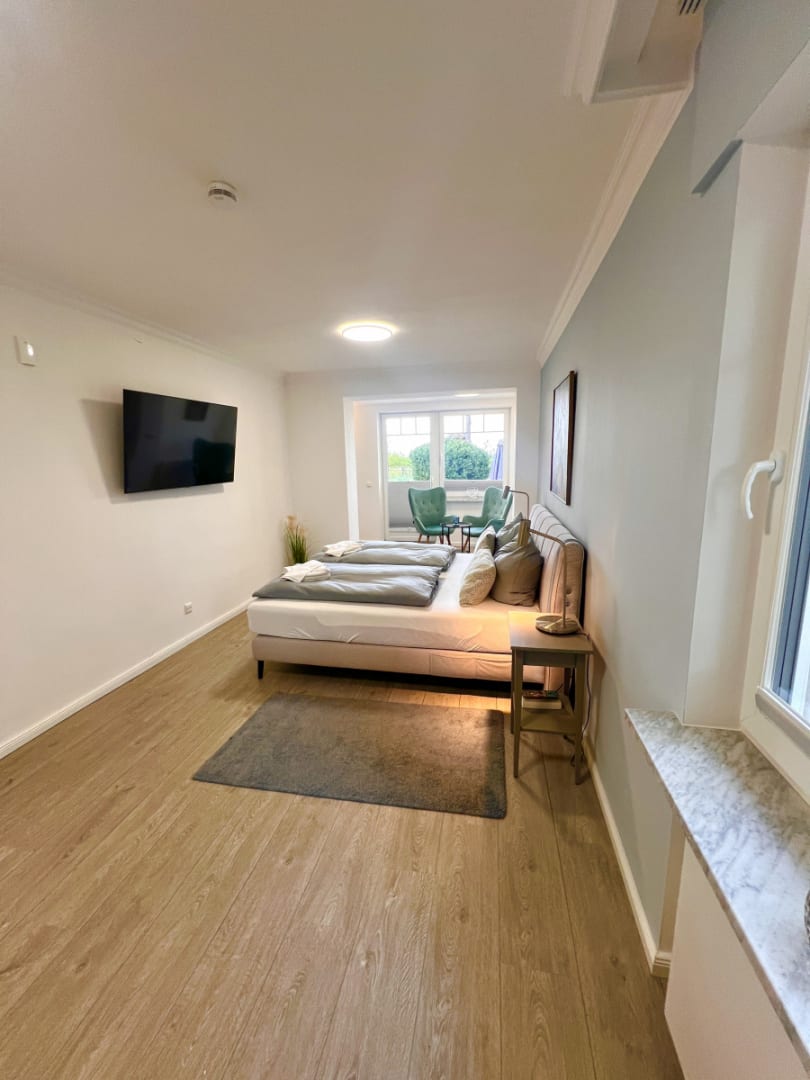 Schlafzimmer mit Doppelbett und Fernseher an der Wand