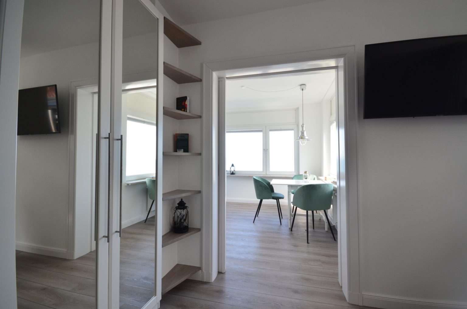 Tür zum Esszimmer, Fernseher an der Wand und ein Kleiderschrank mit Spiegeln