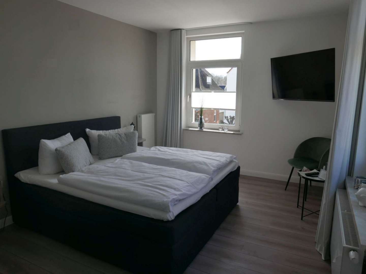 Schlafzimmer mit Doppelbett und Fernseher an der Wand