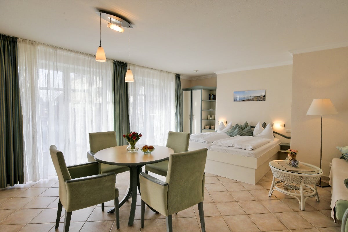 kombinierter Wohn und Schlafbereich, ein Doppelbett im Hintergrund ein Esstisch mit 4 Stühlen