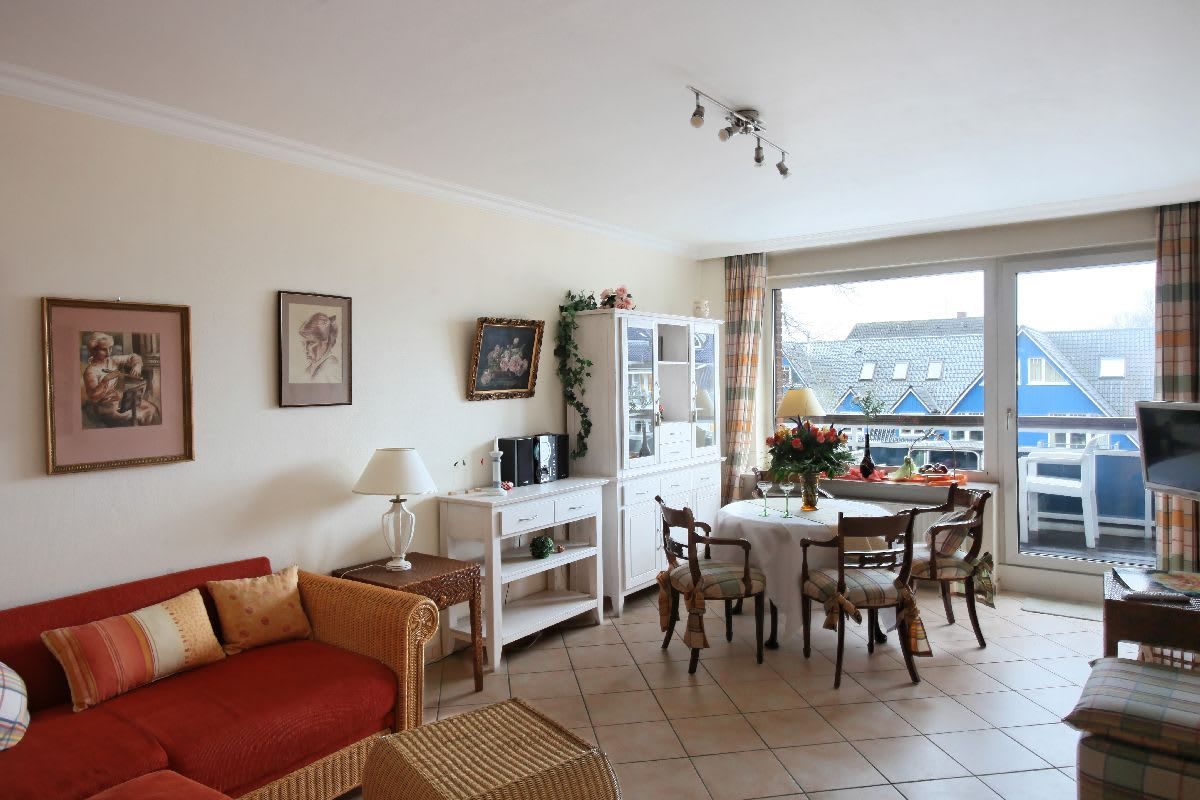 Wohnzimmer mit Sofa und Esstisch, im Hintergrund ist der Balkon