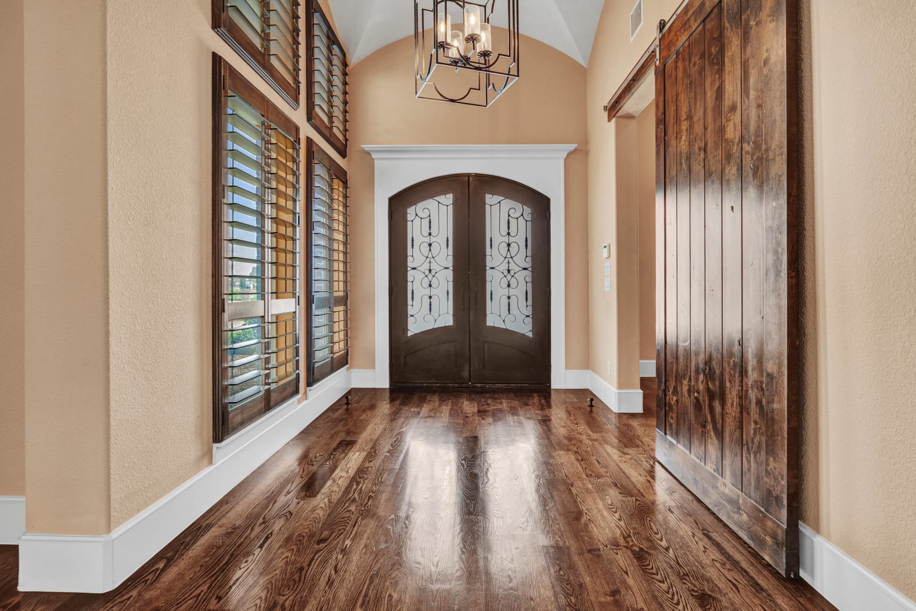 Foyer with iron double doors and glowing hardwood floors in a Lucas, Texas estate