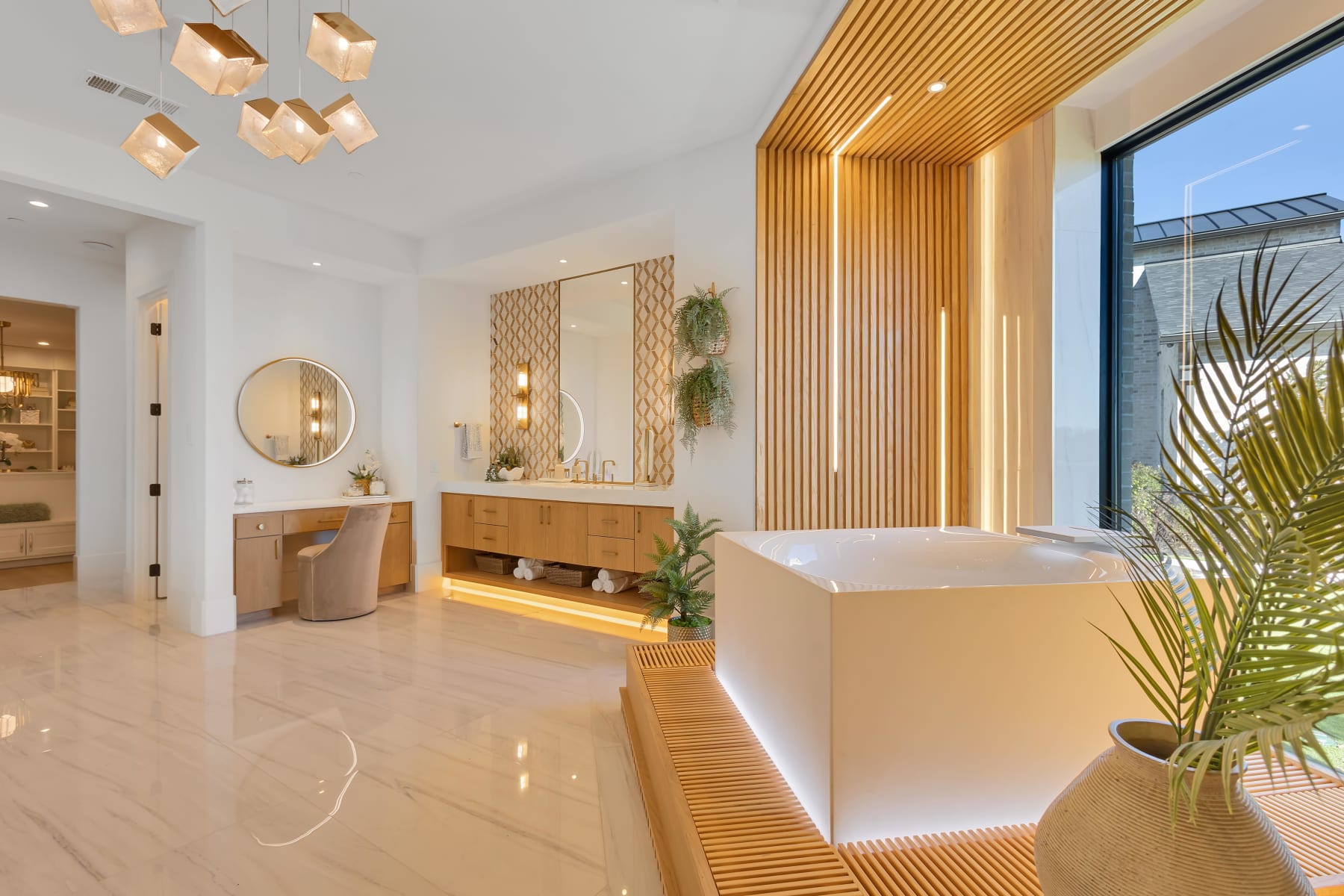 Primary bath with glowing wood slat wall, freestanding tub, and marble floors in Allen, Texas