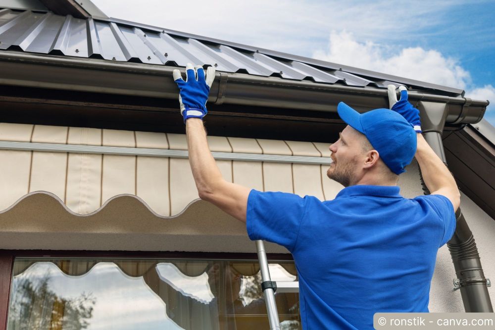 Handwerker montiert eine Dachrinne am Hausdach und richtet sie unter der Traufe aus