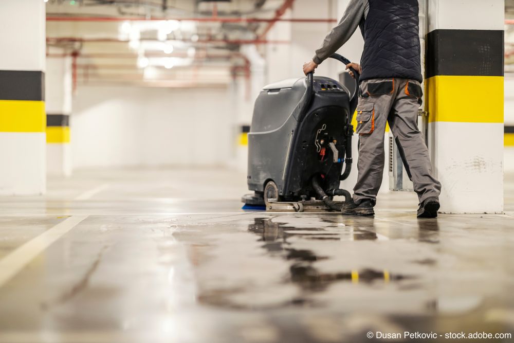 Fachkraft reinigt den Garagenboden mit einer Reinigungsmaschine