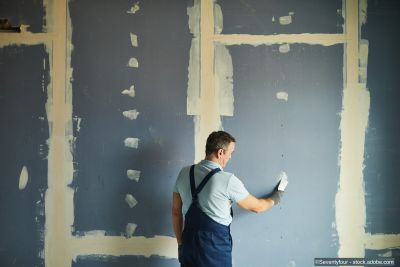 Vue arrière d'un homme âgé rénovant une maison avec des cloisons sèches