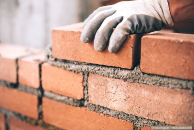 Construire un mur : Gros plan sur un maçon posant des briques sur un chantier de construction