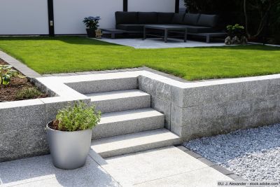 Jardin d'agrément bien entretenu avec mur en pierre et escalier en madriers