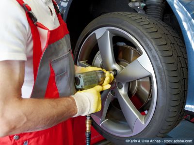 Un professionnel monte des pneus d'été et des jantes avec une clé à chocs sur un pont élévateur