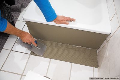 Un professionnel pose des carreaux dans une salle de bains