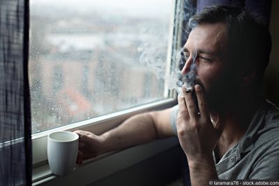 Homme avec une tasse de café du matin fumant une cigarette à la fenêtre 