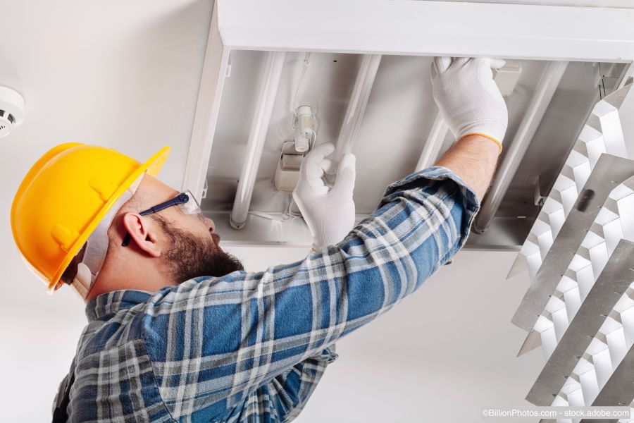 Un électricien installe des spots au plafond