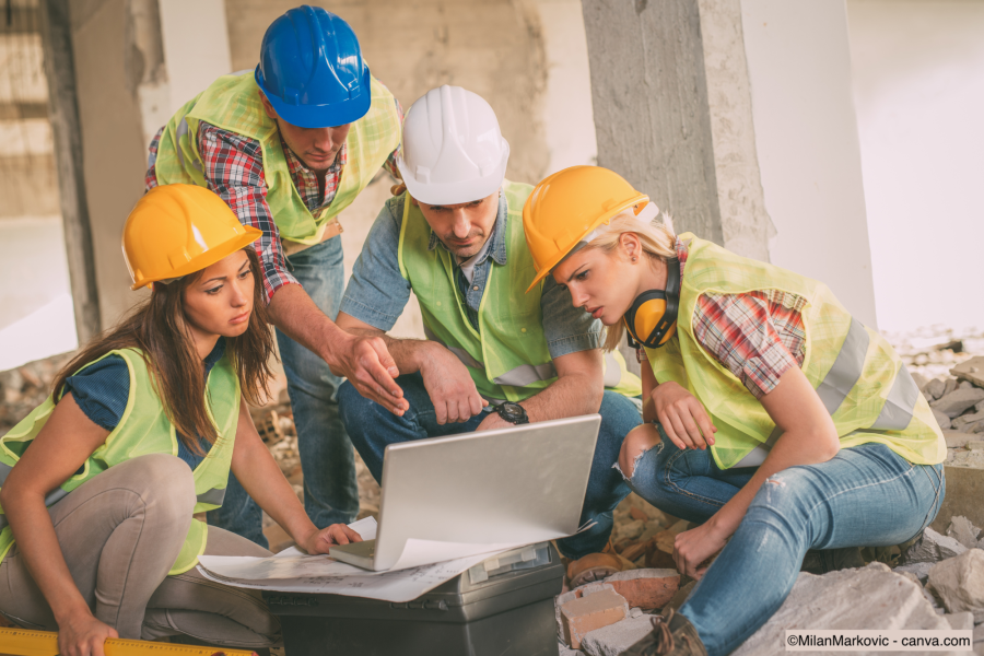 Vier Bauarchitekten prüfen die Umbaupläne eines Hauses am Laptop
