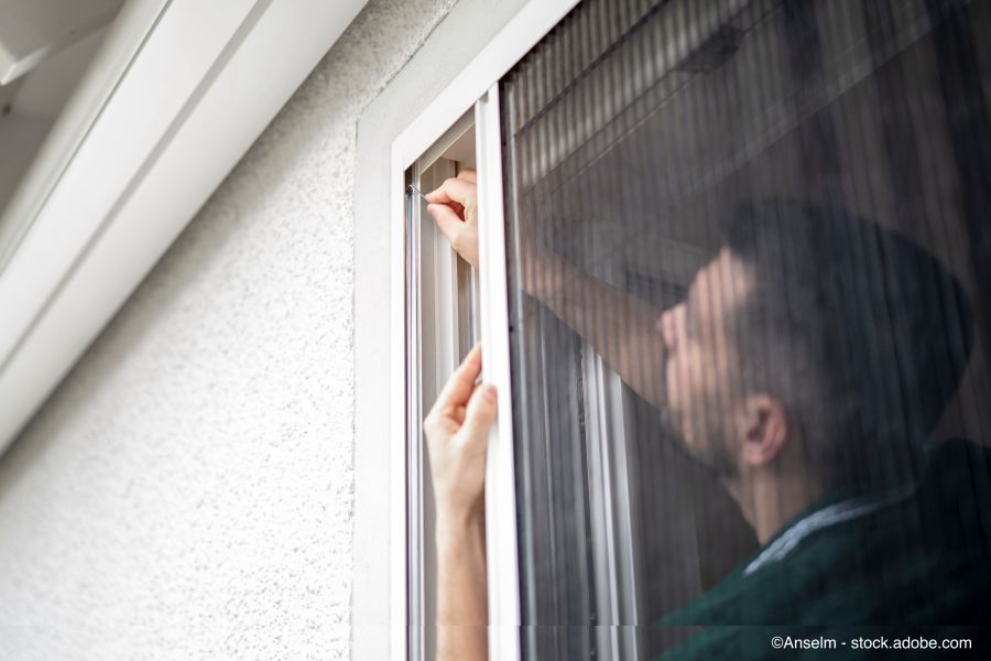 Un artisan sympathique installe des moustiquaires au domicile d'un client