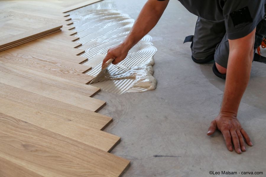 Un poseur de sol colle un parquet