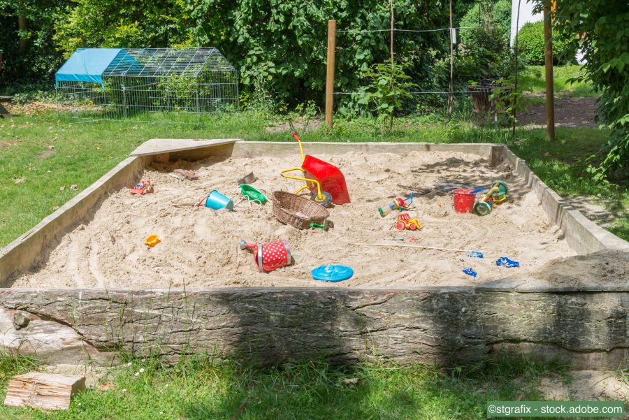 Grosser Sandkasten mit Kinderspielzeug in einem Garten