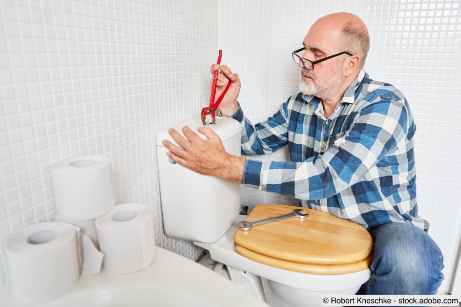 Heimwerker mit Rohrzange repariert den Spülkasten 