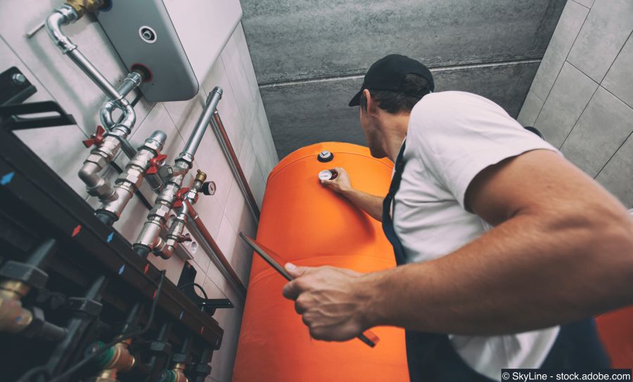 Techniker überprüft die Boiler im Heizungsraum mit einem Tablet in der Hand