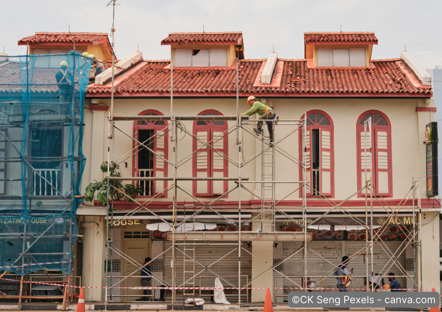 Handwerker auf Geruest renovieren die Fassade eines historischen gebaeudes