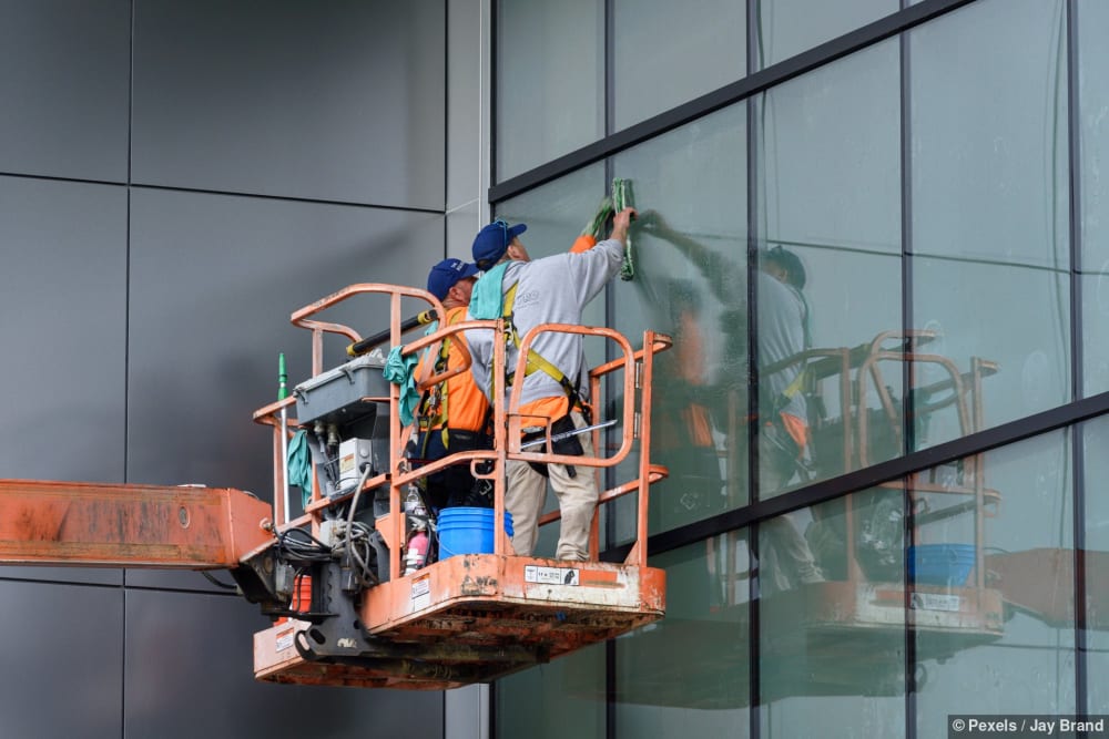 Fensterreiniger arbeiten mit einer Hebebühne an einer fertig gestellten Baustelle eines Hauses