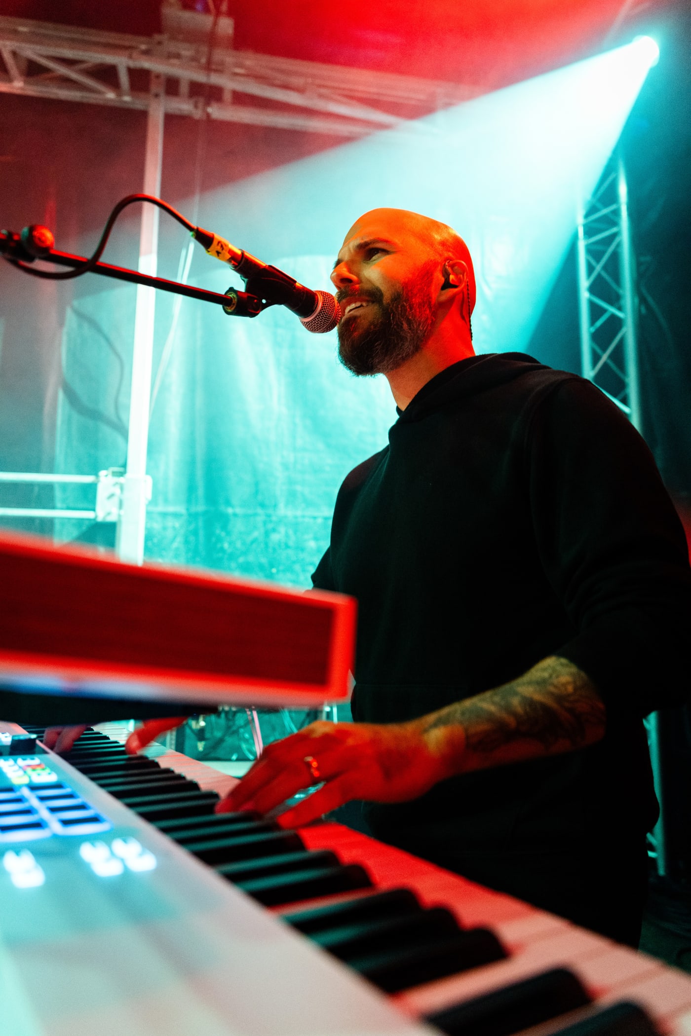 Claviériste et chanteur sur scène, lumières rouges et vertes
