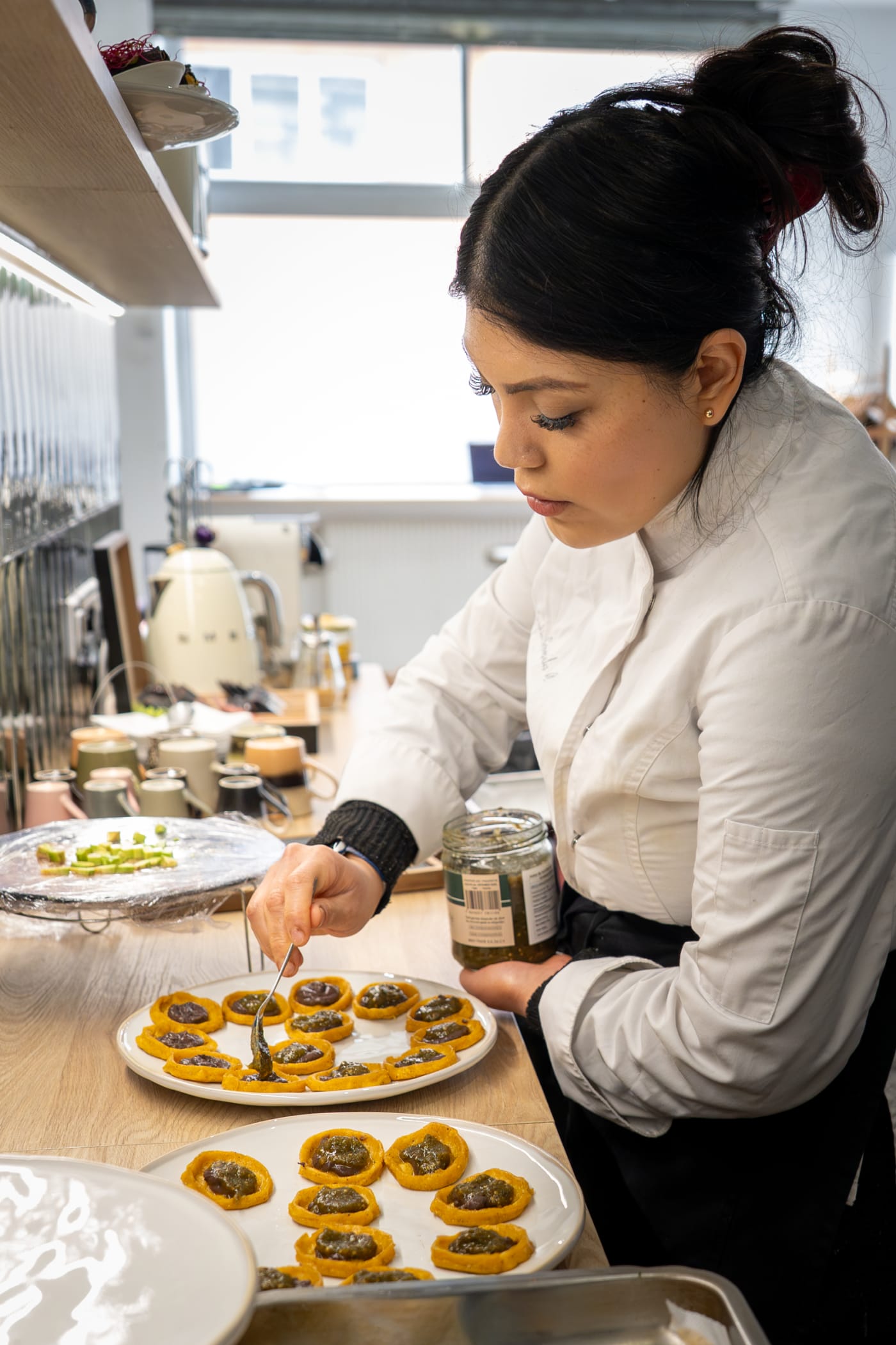 Cheffe en veste blanche dressant des assiettes dans une cuisine lumineuse