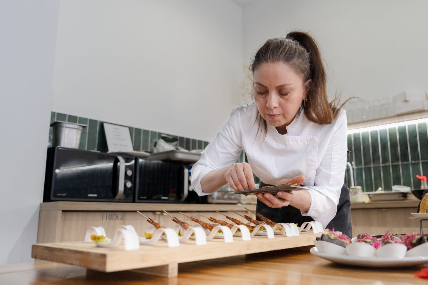 Cuisinière concentrée sur la préparation de ses assiettes, plan de travail au premier plan