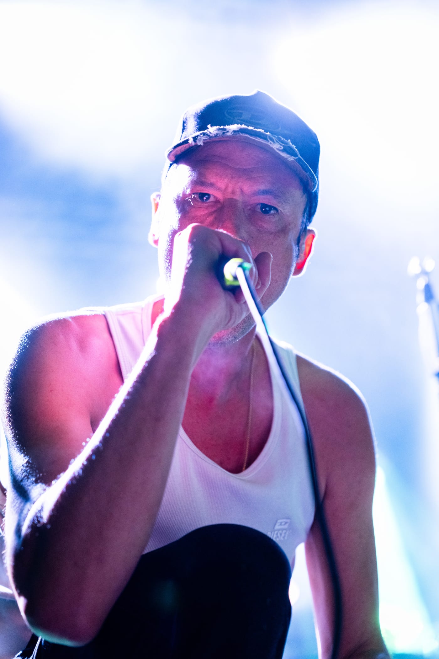 Chanteur au micro, tête levée, devant un ciel clair