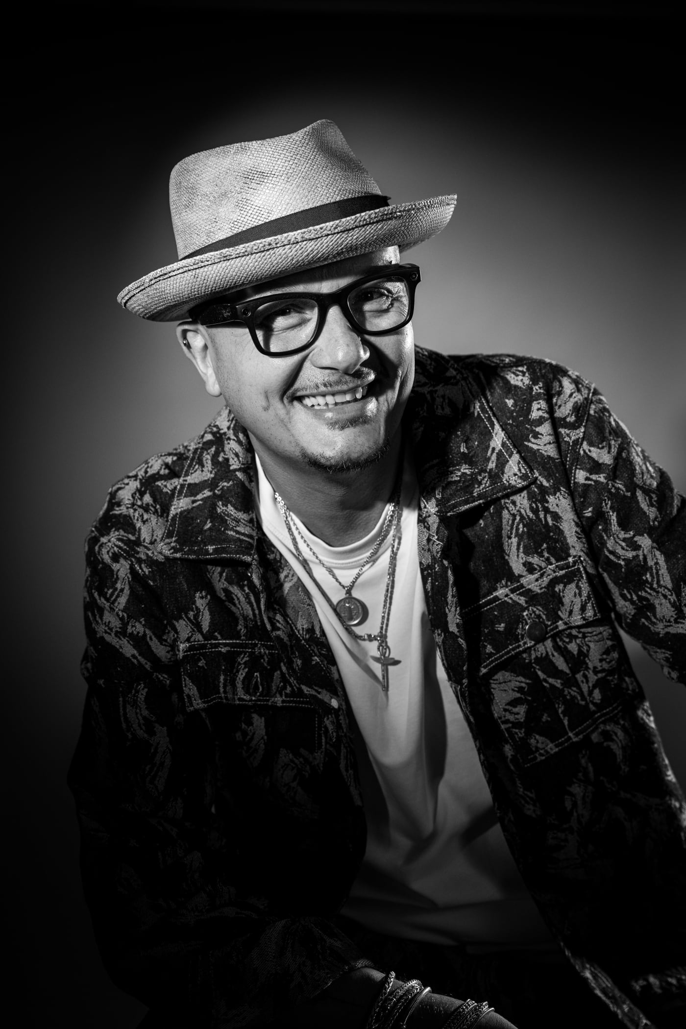 Portrait d’un homme coiffé d’un chapeau et de lunettes, veste à motifs