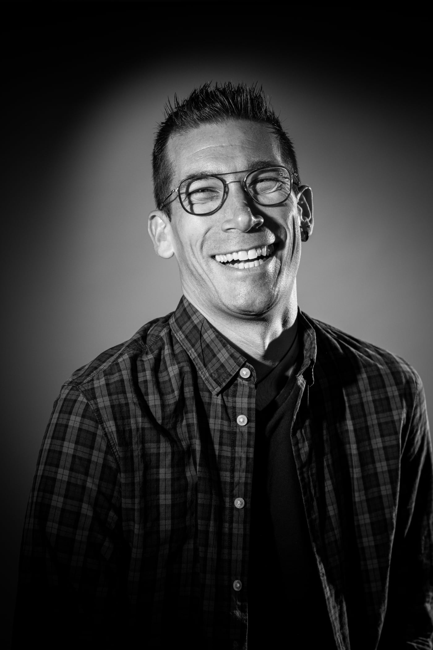 Portrait d’un homme à lunettes souriant, chemise à carreaux