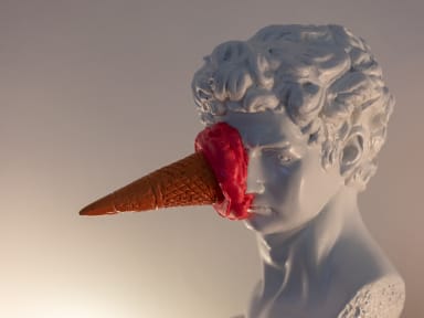 A statue with an ice cream cone stuck to its face