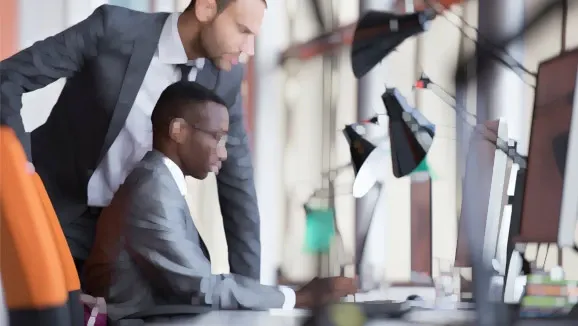 Two people are looking at a screen in an office at work