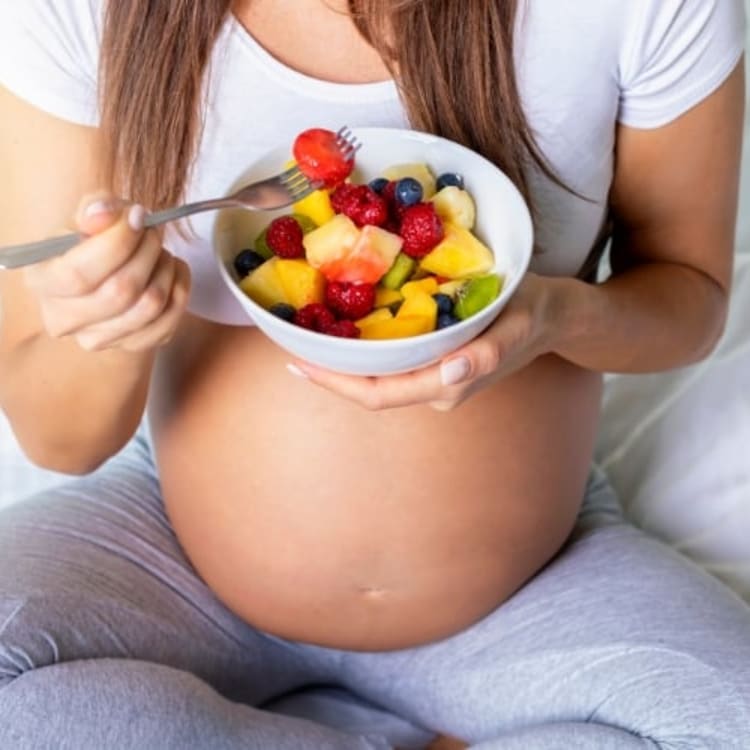 Mujer embarazada comiendo un bol de frutas