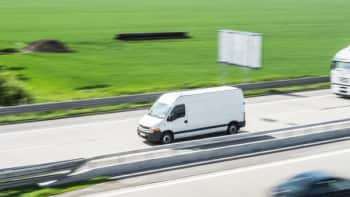 White delivery van driving down the highway