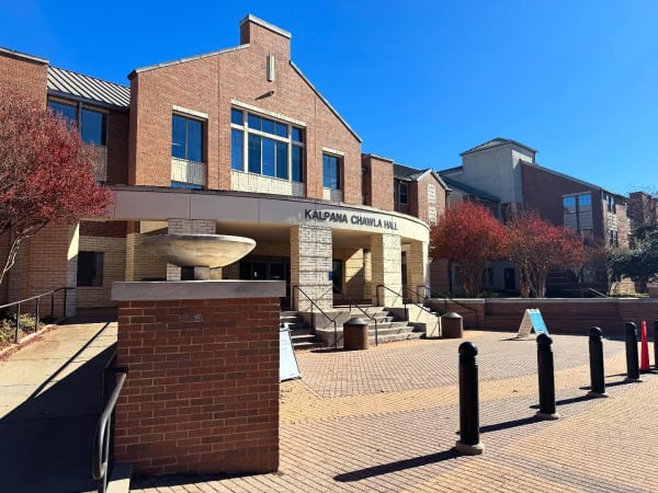 A brick building with a columned entrance and autumn trees