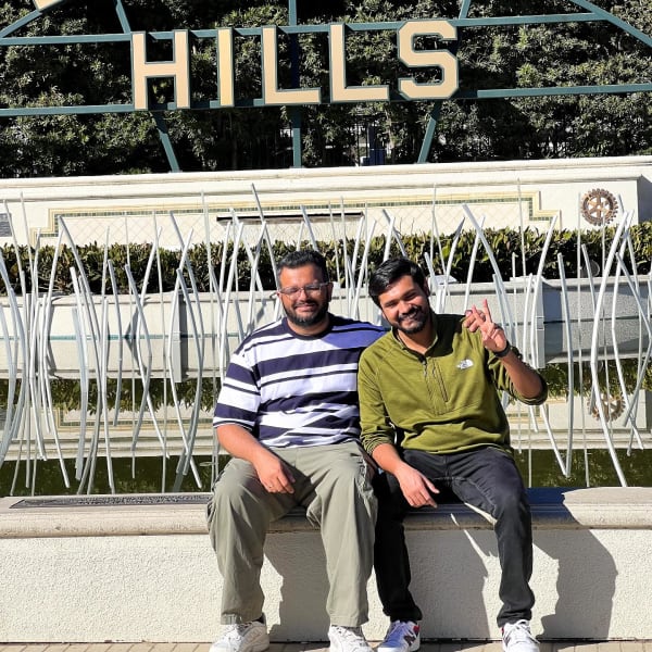 Two people sitting together in front of the Beverly Hills sign