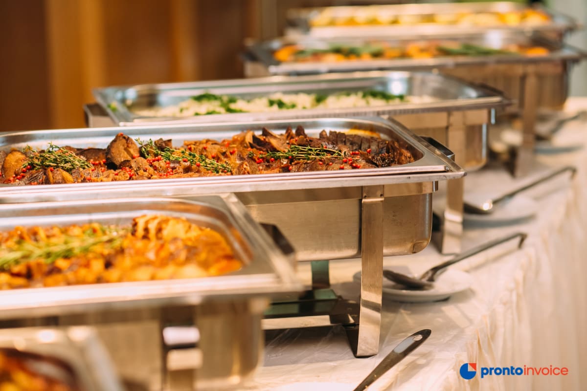 Black female caterer in commercial kitchen checking catering invoice on smartphone