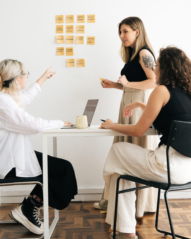 Maiara Minatto conduzindo uma sessão de consultoria com post-its na parede