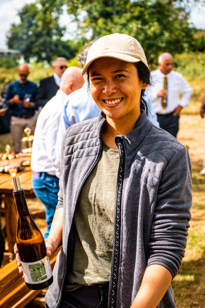 Participante souriante présentant une bouteille de vin blanc