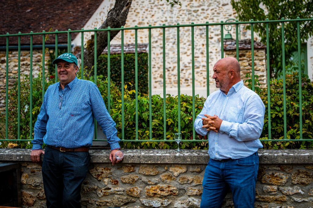 Deux entrepreneurs en discussion appuyés contre un muret en pierre