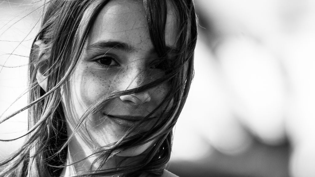 Portrait noir et blanc d’une jeune fille aux cheveux au vent