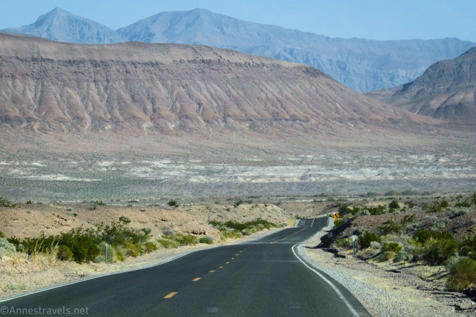 A paved road heading for desert hills and mountains