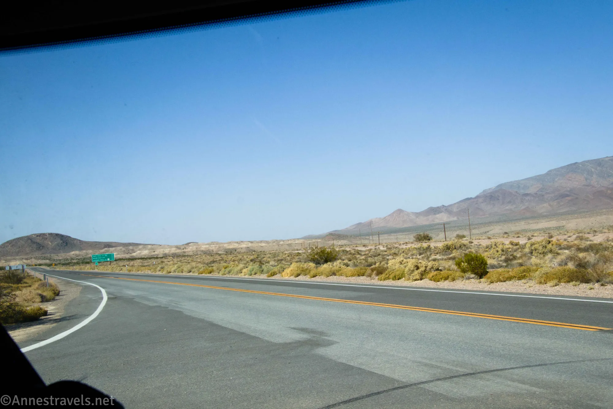 A blacktop road with a yellow stripe down the center in the desert