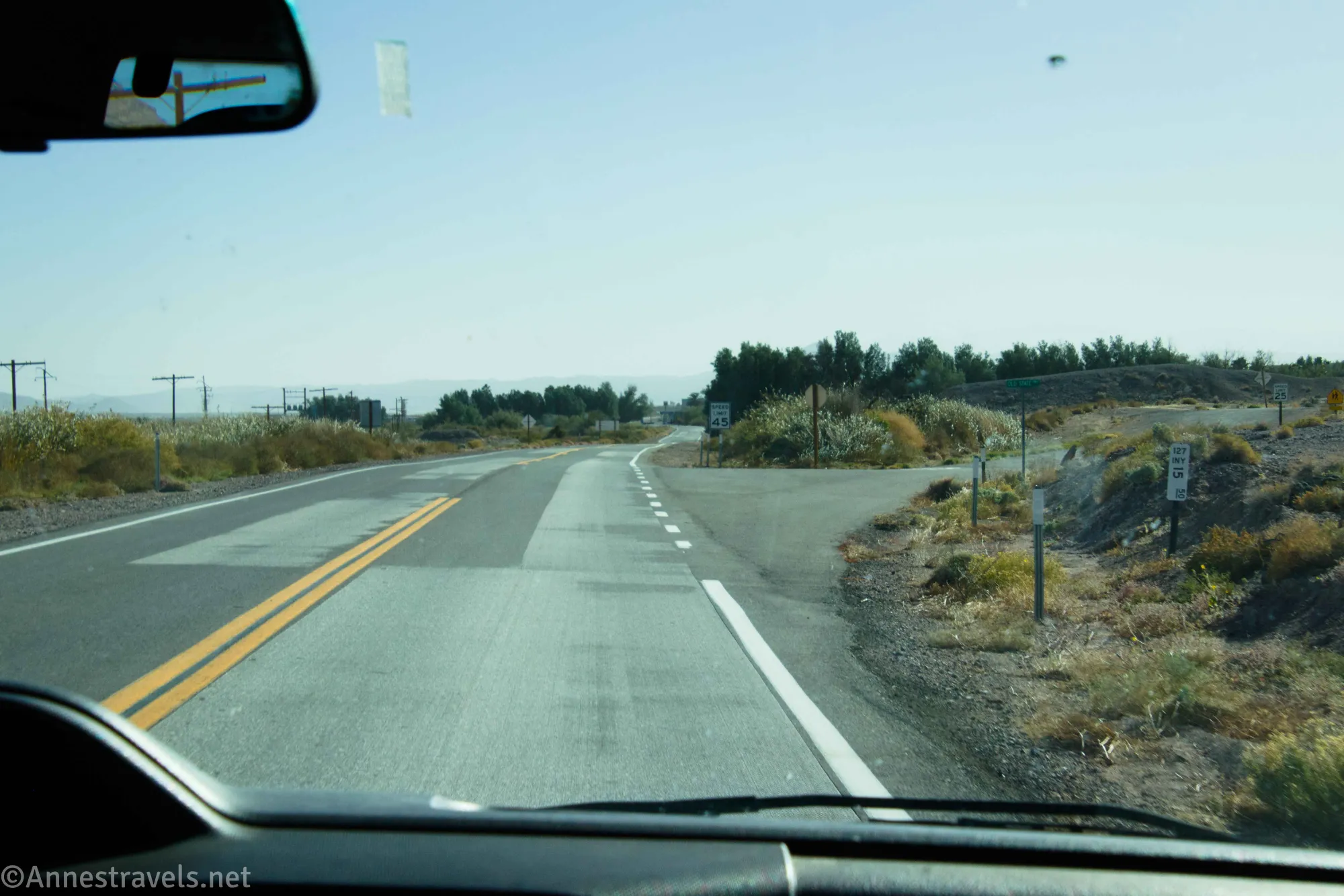 A road through the desert with signs and powerlines