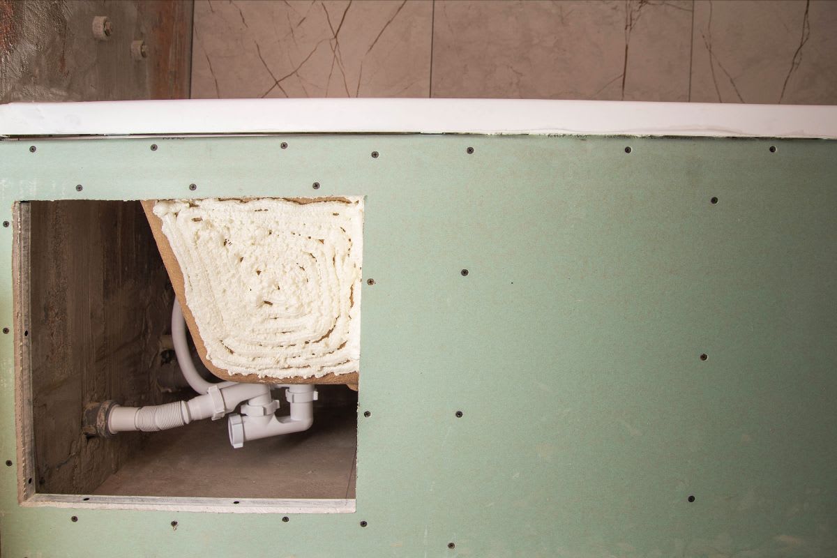 Wannenverkleidung mit ausgesägter Revisionsöffnung. Auf die Verkleidung werden später die Fliesen geklebt. Über die Revisionsöffnung ist der Wannenablauf für Reparaturen frei zugänglich.