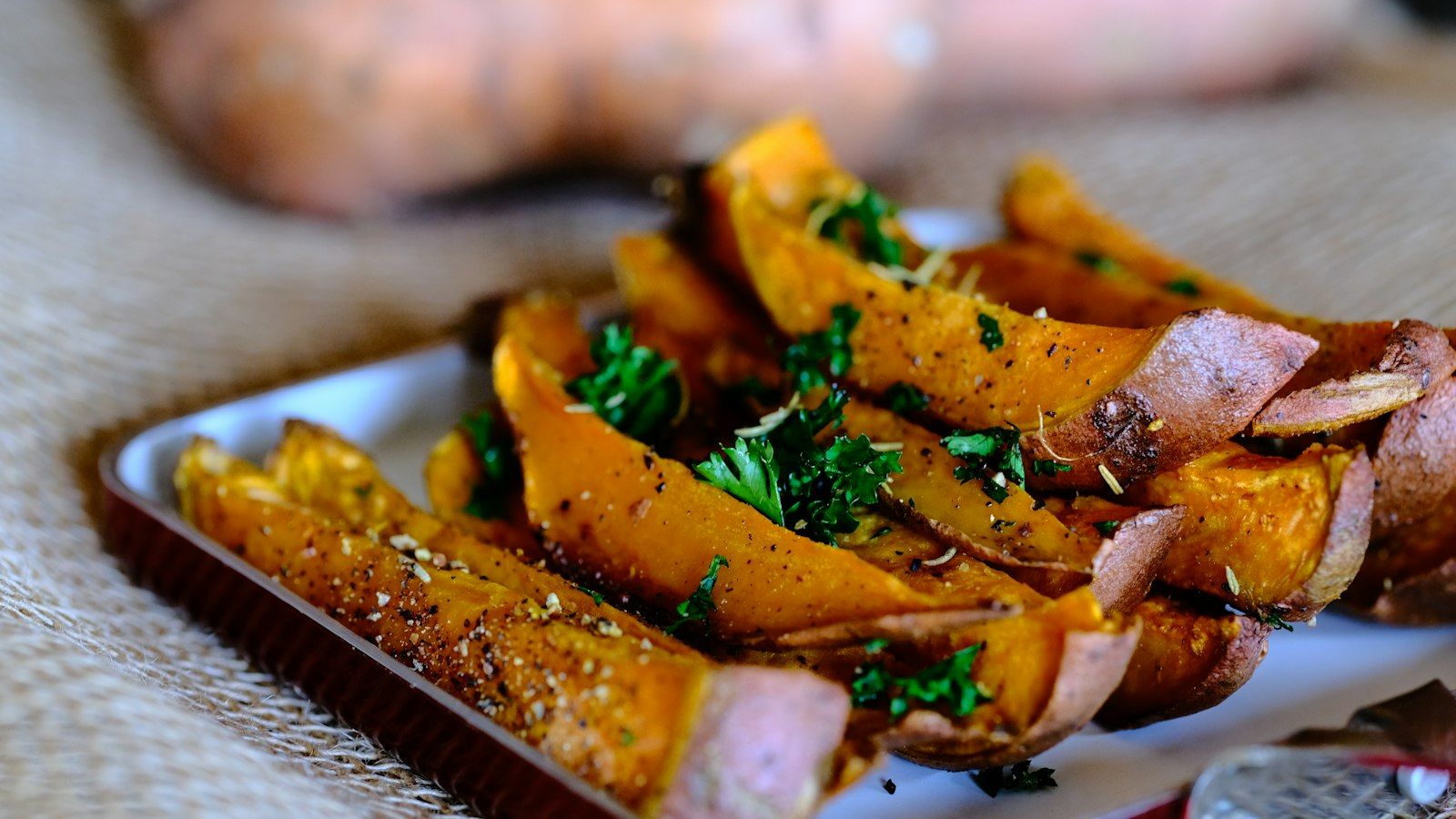Freshly baked sheet pan sausage and sweet potatoes on a dark baking tray